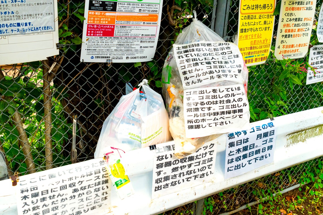 ごみの分別を呼び掛ける張り紙が並ぶ集積場（PIXTA）