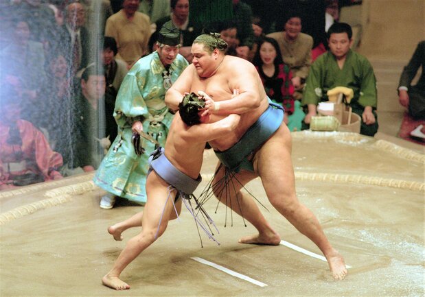 身長2m・体重230kg超の横綱曙のパワフルなもろ手突きにもひるまない。「体格差はハンディにはならない」との挑戦者魂も身上だった(1995年1月12日、東京・両国国技館) 時事