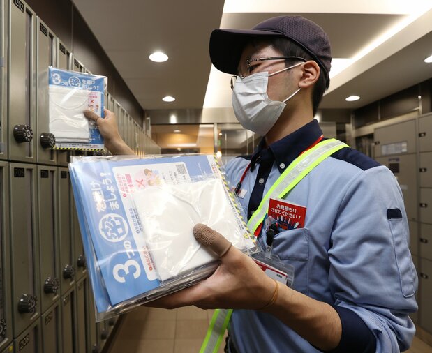 A postal worker delivers “Abenomasks,” cloth masks distributed by the government to every household in Japan, in Ōsaka on May 12. (© Jiji)
