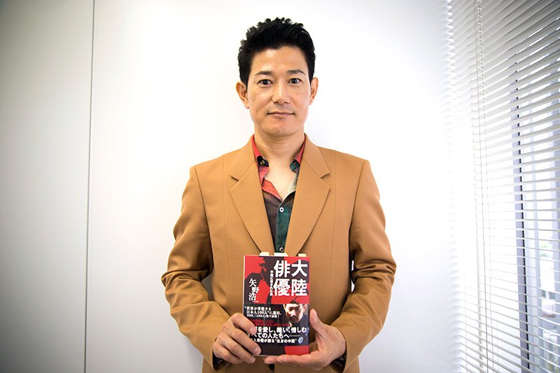 矢野浩二，手上拿着自己的著书