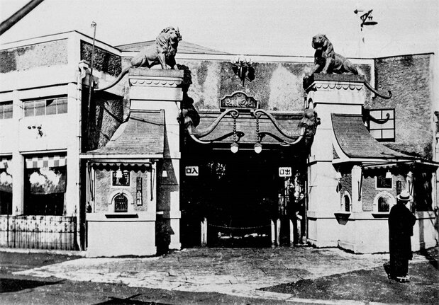 مدخل الحديقة في عام 1926. توافد الناس لزيارة الحديقة عندما تم الإعلان عن ولادة خمسة أشبال من النمور، وكان بمثابة حدث غير عادي في ذلك الوقت. ويقال إن الإمبراطور تايشو زارها متخفيًا (إهداء من أساكوسا هاناياشيكي)