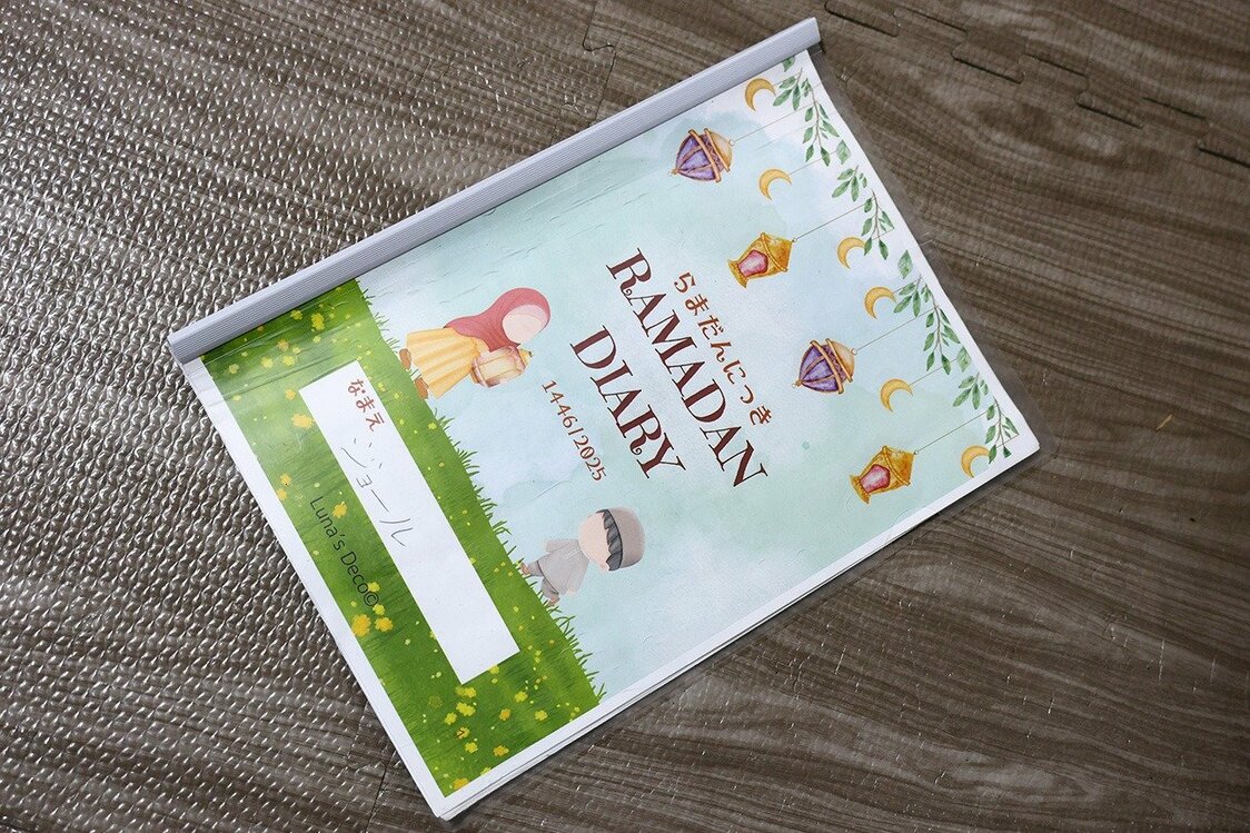 ابتكرت عائشة ”كتاب رمضان“، حيث يمكن للأطفال تسجيل يومياتهم الرمضانية، مما يساعدهم على توثيق تجربتهم والتفاعل مع أجواء الشهر الكريم بطريقة ممتعة ومفيدة. (© نومورا كازويُكي)