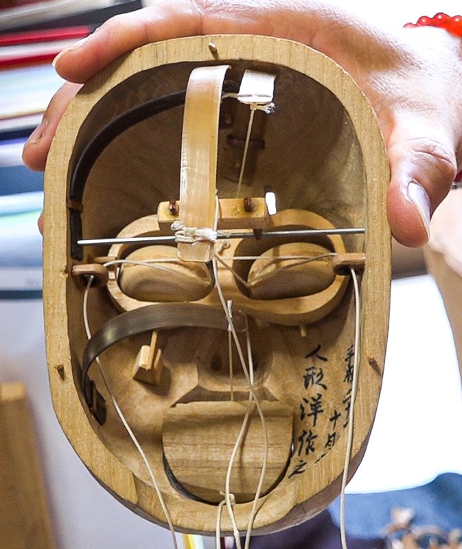 Le mécanisme intérieur d’une tête de marionnette. Au centre, on aperçoit le poil de fanon de baleine (kujira no hige) qui fait office de ressort et permet de le mettre en mouvement.