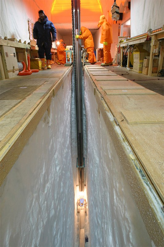 Extraction d’échantillons de carottes de glace à la station Dome Fuji, située à l’intérieur du continent, en janvier 2005. La partie éclairée montre la perceuse pénétrant la glace. Les chercheurs ont excavé la glace jusqu’à 3 km de profondeur.