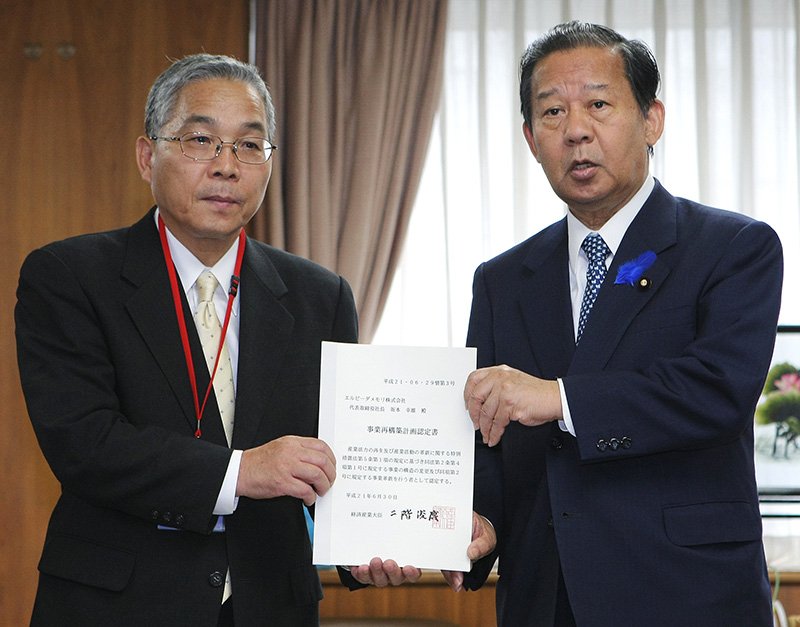 尔必达内存公司的坂本社长从二阶俊博经济产业大臣（时任，右）手中接过基于产业活力再生特别措施法的认定书（2009年6月30日，图片：时事通信社）