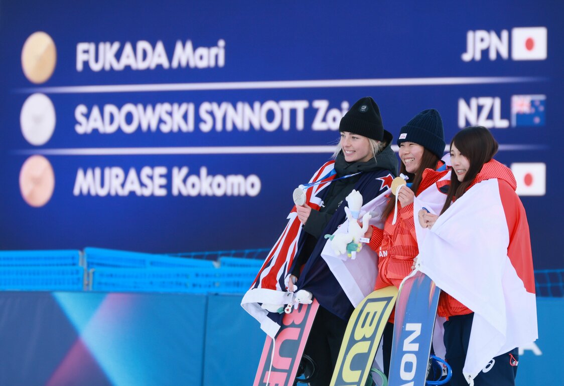 スノーボード女子スロープスタイルの金メダルを手にする深田茉莉（中央）。右は銅メダルの村瀬心椛、左は銀メダルのゾイ・サドフスキシノット（ニュージーランド）＝2026年2月18日、イタリア・リビーニョ（時事）