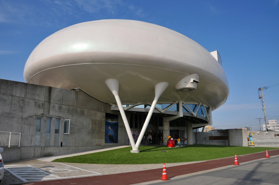 旧北上川沿いに建つ円盤形の個性的な施設。石ノ森は、万物を表現できる「万画（よろずが）＝萬画」と提唱し、自らも「萬画家」と称していた