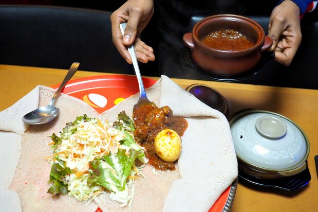独特の酸味と食感のインジェラに小鍋でアツアツに煮込まれたドロワットを添えてもらう。食べてみると、見た目以上にボリュームを感じる 写真=渕貴之
