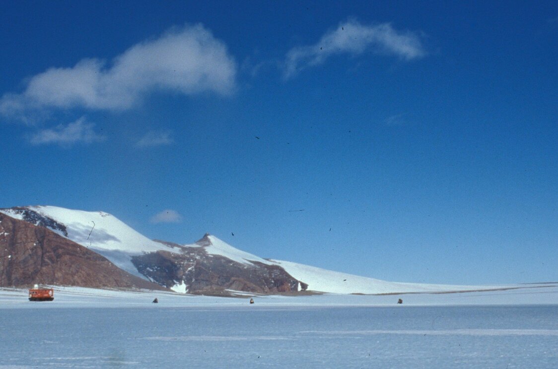 陨石搜索工作现场，3辆雪地摩托与大型雪地车并行，在冰原上搜寻陨石