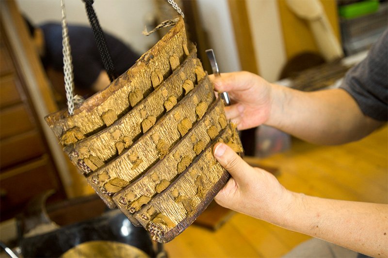 Restauración de una armadura de la segunda mitad del siglo XVI (periodo Muromachi). Hay que retirar el hilo viejo de las saneita, las piezas de hierro y cuero sobre las que se aplicaba el pan de oro, para agregar hilo nuevo