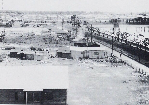 La salida oeste de la estación de Shinjuku en 1958. En la parte derecha se observa el colosal embalse de agua de la Planta Purificadora de Yodobashi. Yomigaetta Tokio (El resurgir de Tokio). (Biblioteca Nacional de la Dieta)