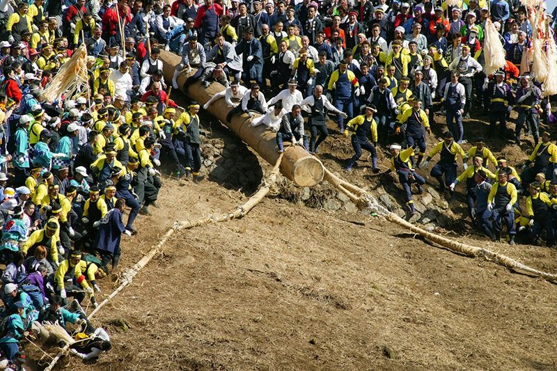 御柱祭的「木落」。氏子（祭拜同一氏神的當地居民）騎在巨木上往山下滑落