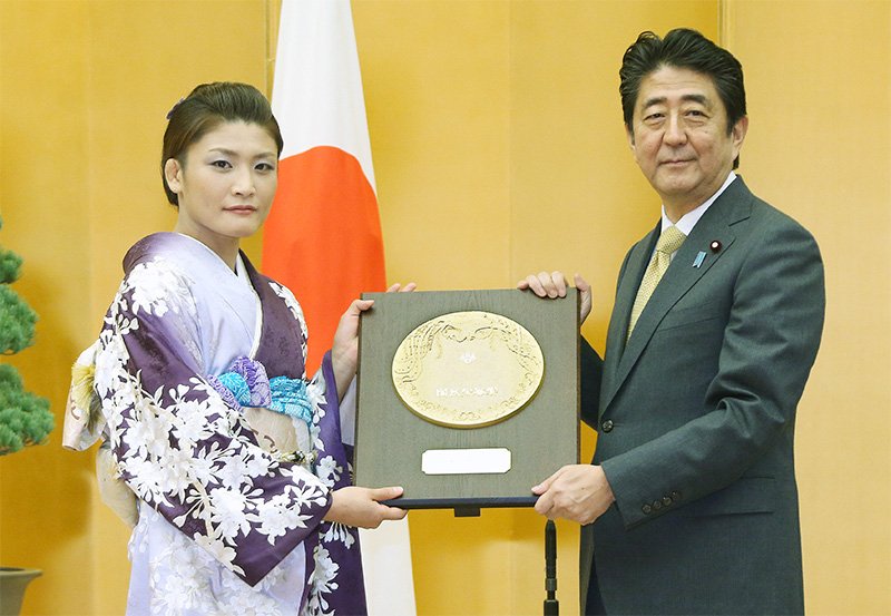 Ichō Kaori (a la izquierda) recibe el escudo del Premio de Honor del Pueblo de manos del primer ministro Abe Shinzō en Tokio el 20 de octubre de 2016. (© Jiji)