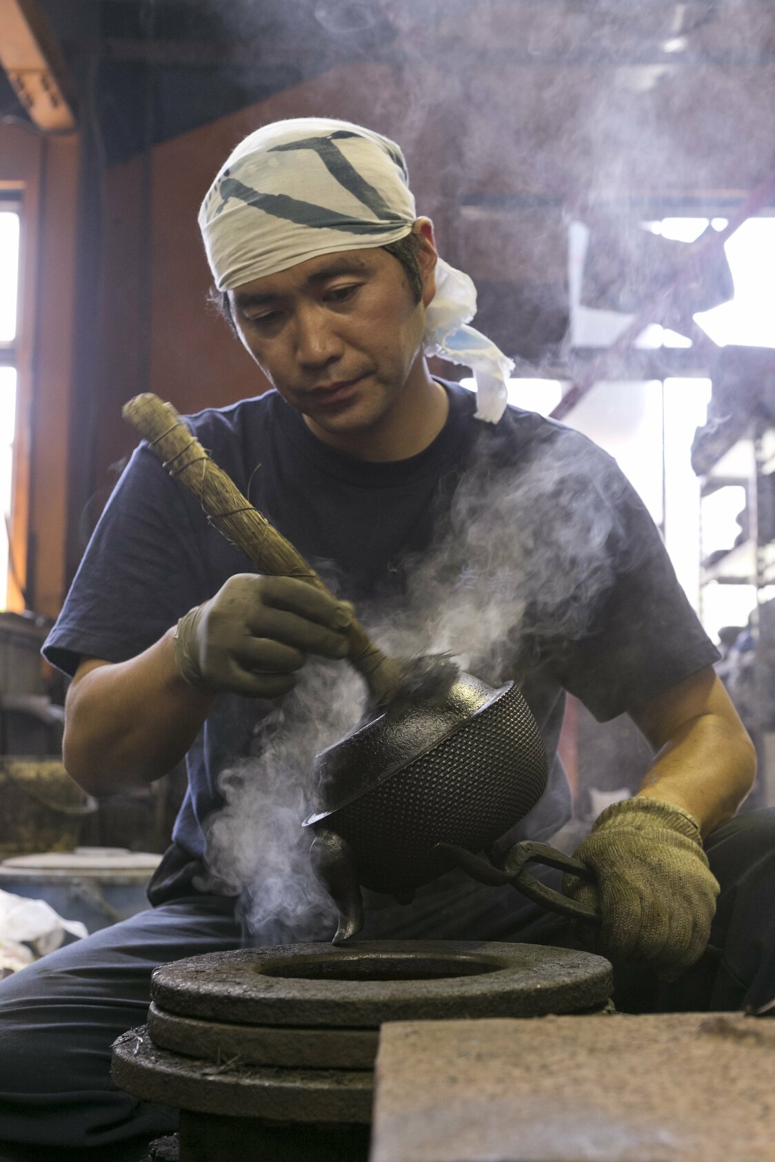 生产作坊里的上色工序。以大约250度的温度加热铁壶，将黑漆烧烙在其表面  图片提供：岩铸