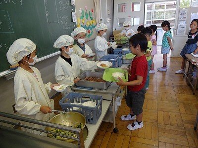 东京都小平市的一所小学的学生正在给同学分发午餐。一到中午时分,日本全国各地的小学都可见到这样的风景