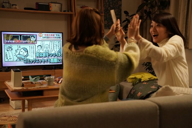 コミックエッセイ「京都老舗赤裸々リポート」がテレビで紹介され、喜ぶまどかとイラスト担当の莉子(小野寺ずる) ©2025「ぶぶ漬けどうどす」製作委員会