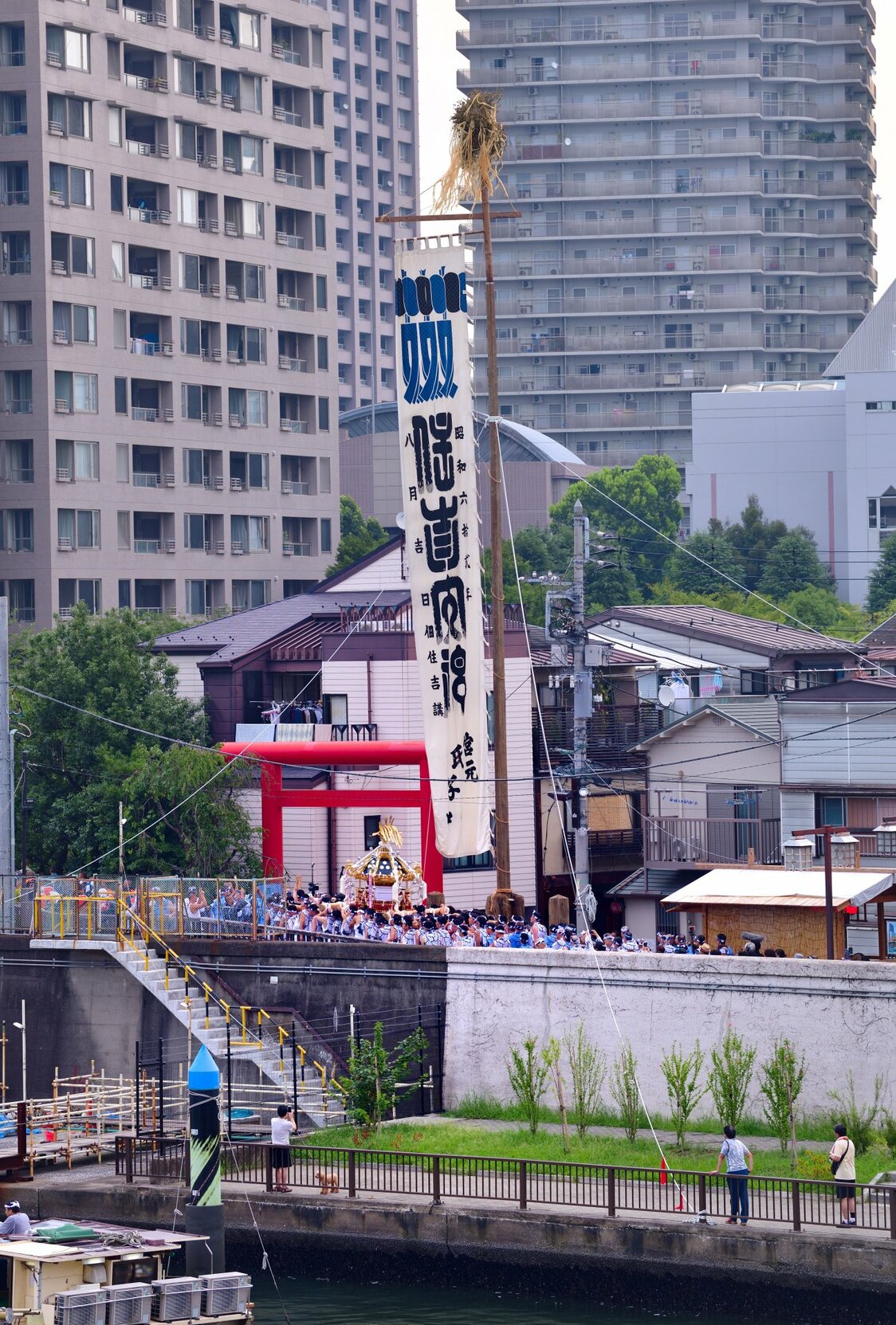 石川島の船着場へと向かい、大幟の下を巡幸する八角神輿