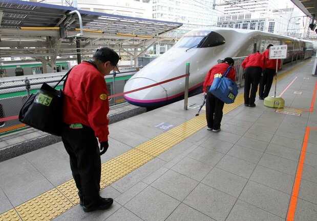東京駅に到着する列車の乗客を礼で迎える清掃スタッフ（PIXTA）