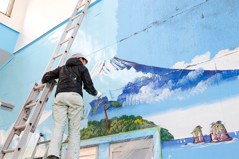 Tanaka usa un rodillo para pintar sobre el mural anterior
