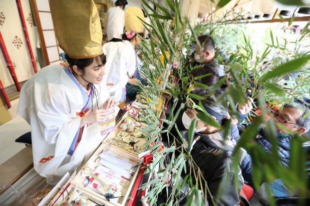 Des femmes coiffées de chapeaux traditionnels distribuent les fukuzasa. (Jiji)