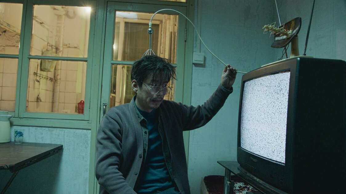 「宇宙の異常な波動はテレビの砂嵐を通じて観測できる」とタンは力説する　©G!FILM STUDIO[BEIJING]Co.,LTD. ALL RIGHTS RESERVED.