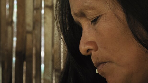 Pastora, la femme du chef du village, mâche le manioc et le recrache en préparation de la chicha. (© Akimi Ota)