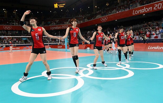 Araki (left) leads the Japanese team onto the court to greet fans following a match at the 2012 London Olympics. (© AFP/Jiji)