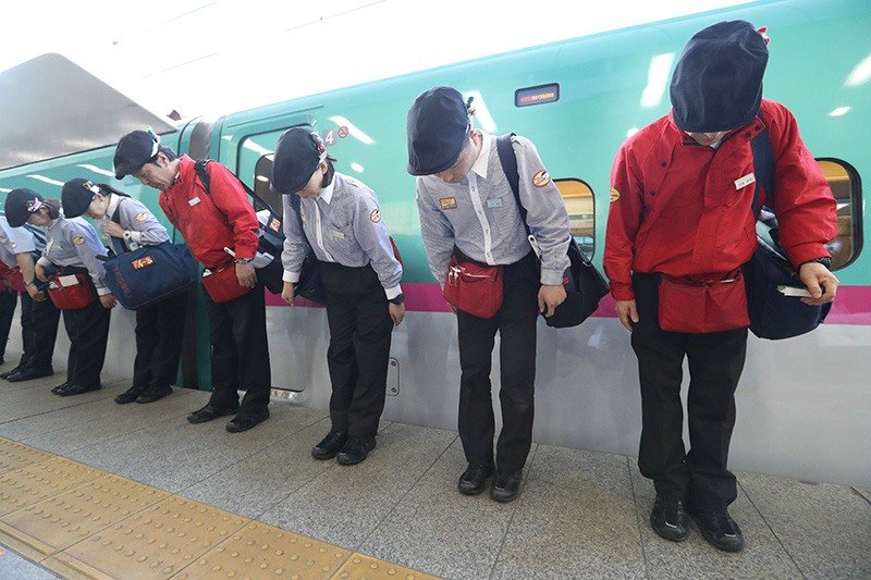 El personal saluda tras finalizar la limpieza del interior de los vagones del Shinkansen en la estación de Tokio de JR (Jiji Press).