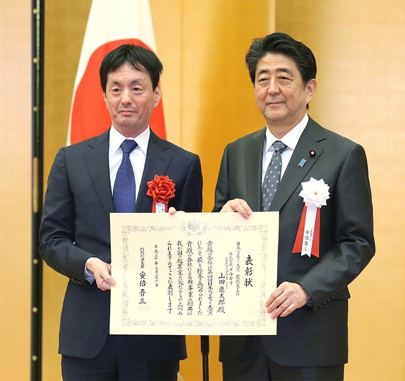 Mercari CEO Yamada Shintarō (left) with Prime Minister Abe Shinzō at the award ceremony for the Fourth Nippon Venture Awards on February 26, 2018, at the Prime Minister’s Office. (© Jiji)
