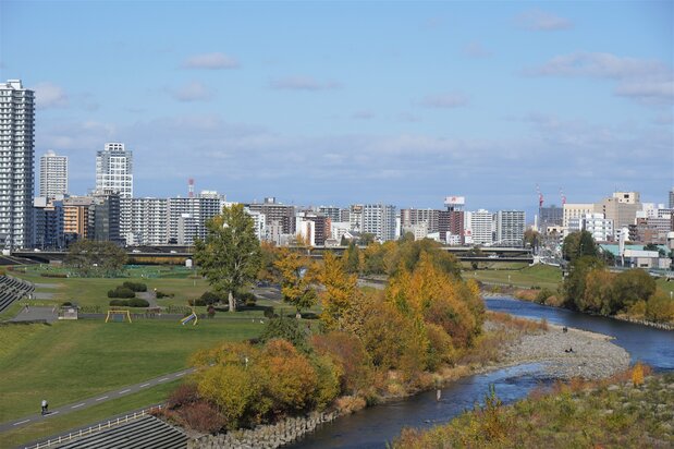 ゆっりたと流れる川の向こうに札幌都心部が見える（撮影 : 前田明裕）