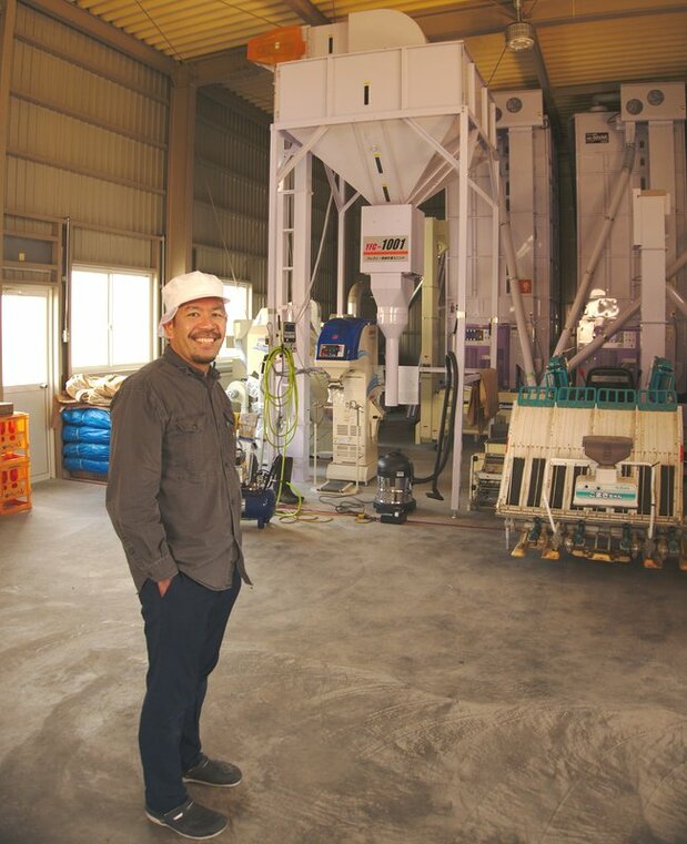 The brewmaster poses in front of a rice weighing/packing machine, another rarity for a sake producer to own.