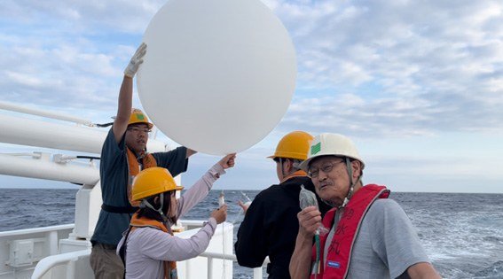 The author, right front, and researchers from Mie University prepare to release a weather balloon from a research vessel off Japan’s northeastern Pacific coast in June 2025. (© Tachibana Yoshihiro)
