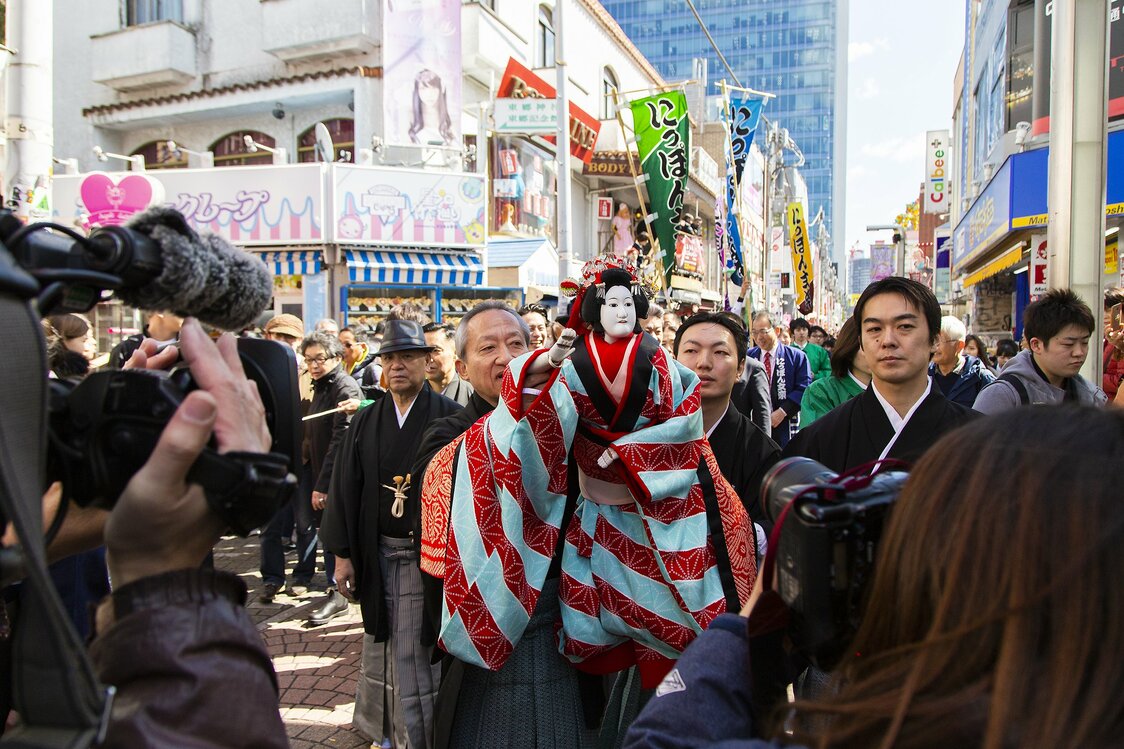 見物客に小さく手を振る人形