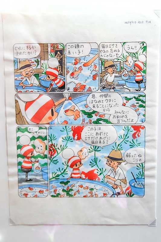 これまでの安野作品とは大きくタッチが異なる「オチビサン」。展覧会では子ども用衣類や手拭いなどのキャラクターグッズを販売