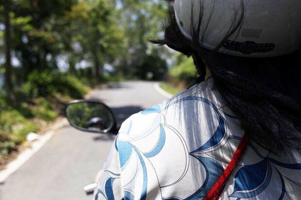 曲がりくねった山道をバイクで走る筆者(野崎志乃撮影)
