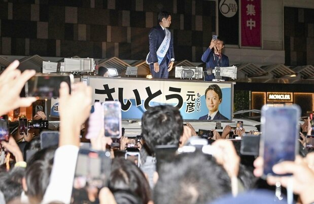 兵庫県知事選の選挙戦最終日、スマートフォンを掲げる大勢の有権者の前で街頭演説する斎藤元彦氏=2024年11月16日、神戸市(共同)