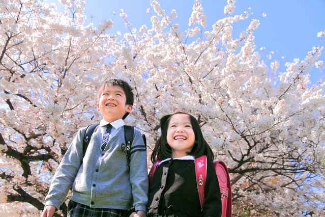 Dos estudiantes de primero de Primaria posan delante de un cerezo.