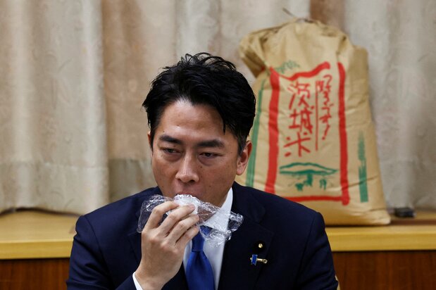 El ministro de Agricultura, Silvicultura y Pesca, Koizumi Shinjirō, prueba un onigiri como parte de una prueba de sabor a ciegas el 29 de mayo de 2025. (© Reuters)