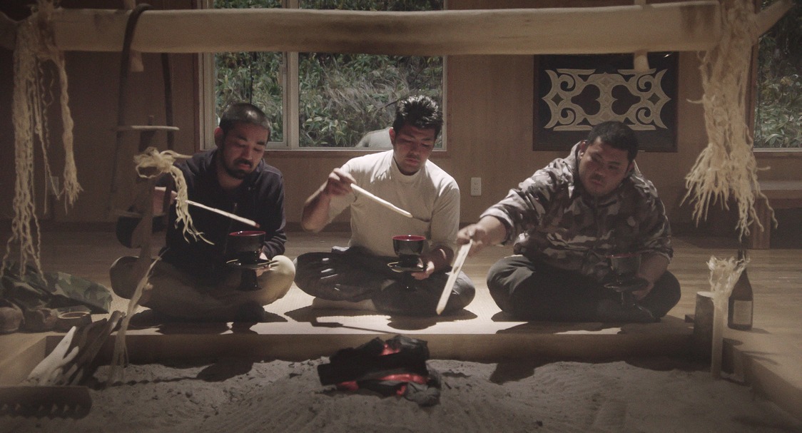Shige, su amigo Satoshi y Ryūtarō informan a los dioses de que han elaborado un inaw para ofrendarlo en el lugar de la pesca. (© 2024 Takeshi Fukunaga/AINU PURI Production Committee)