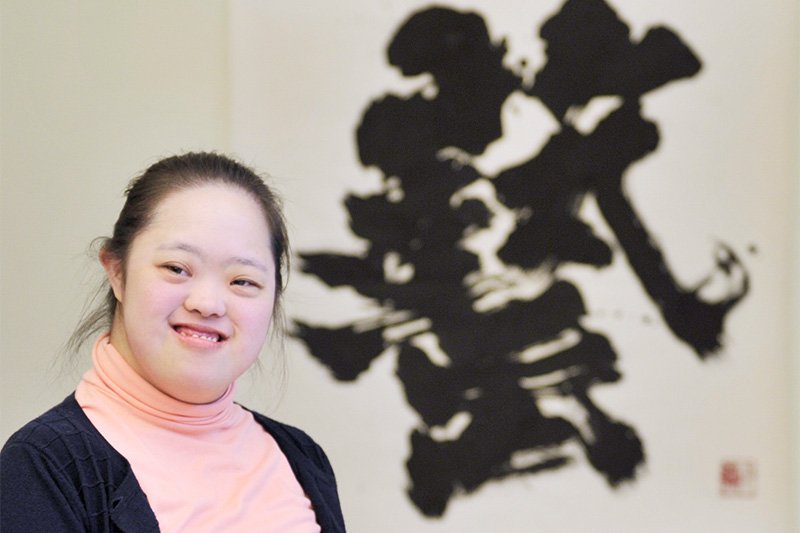 Kanazawa posa sonriente delante de su obra Arte.