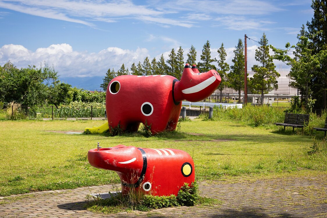Akabeko Park on the outskirts of Aizuwakamatsu features akabeko-themed playground equipment, including a drinking fountain and slide. (© Nippon.com)