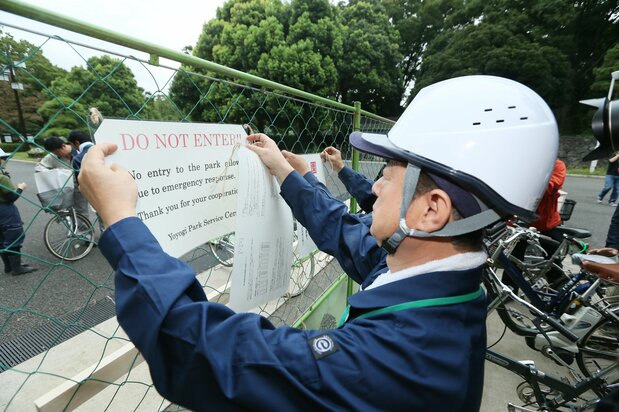 採集した蚊からデング熱ウイルスが検出されたことを受け、代々木公園閉鎖の張り紙をする公園関係者＝2014年9月4日、東京都渋谷区（時事）
