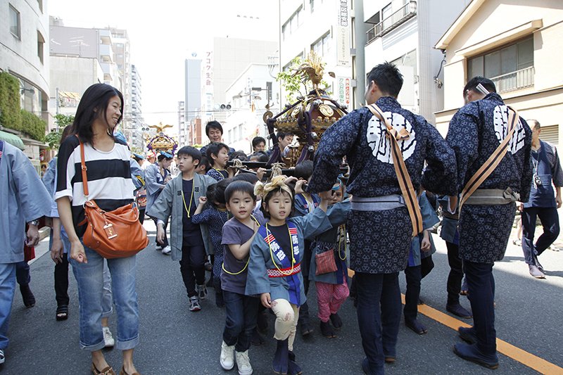 A mother looks on as her children help to carry the children’s “mikoshi.”