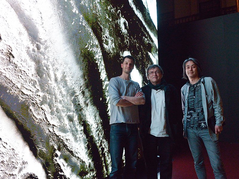 Standing in front of the high-definition monitor used for the Mars, a Photographic Exploration exhibit are (from left to right) Oliver Franz, the exhibition designer; Xavier Barral, the curator; and Takatani Shirō, the artist who prepared the video installation.