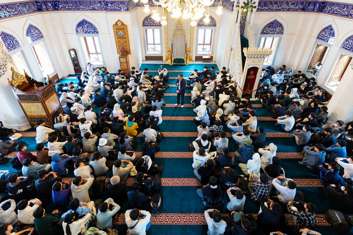 عدد كبير من الطلبة اليابانيين يجلسون داخل جامع طوكيو للاستماع لحديث شيموياما عن الإسلام. (© Nippon.com)
