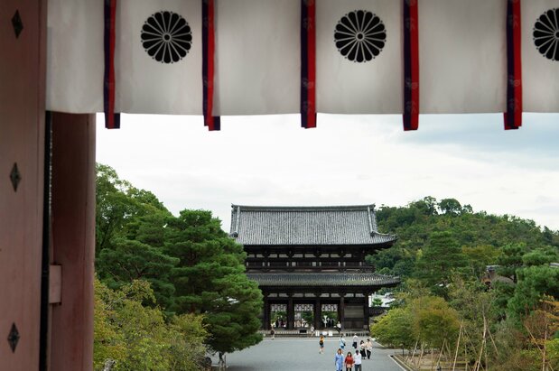 天皇家を表す菊花紋章越しに二王門を望む。仁和寺境内の散策は無料で、御殿や霊宝館、特別展の入場には拝観料が必要