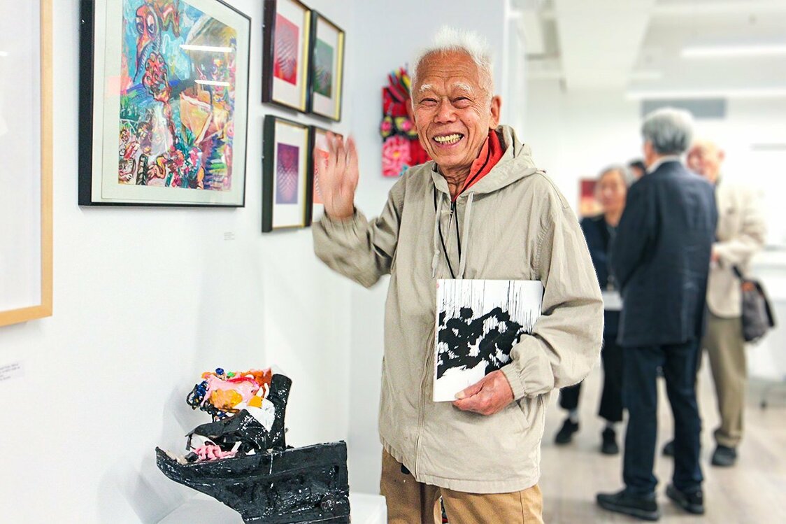 2023年5月 JAA（ニューヨーク日系人会）のグループ展でのギュウちゃん。木やワイヤー、段ボールなどで作った最新作「ピアニスト」などと共に　©安部かすみ