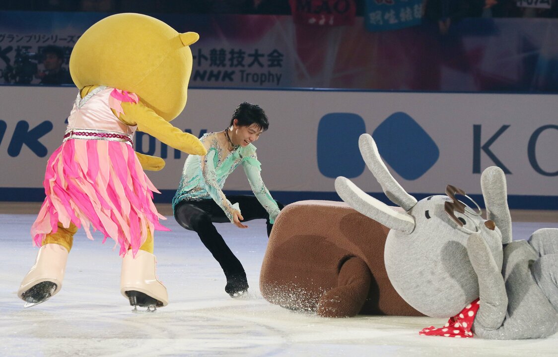 Hanyū Yuzuru tiende la mano para ayudar a Dōmo-kun, la mascota de la NHK, que se cayó durante la exhibición de patinaje del 29 de noviembre de 2015. (© Jiji)