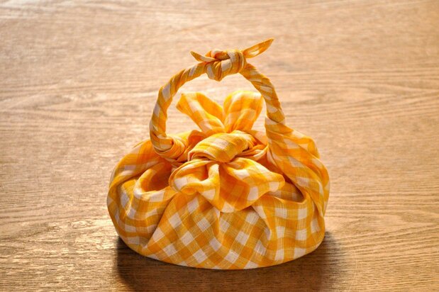 Una fiambrera envuelta en un furoshiki. Un nudo en forma de lazo y una asa.