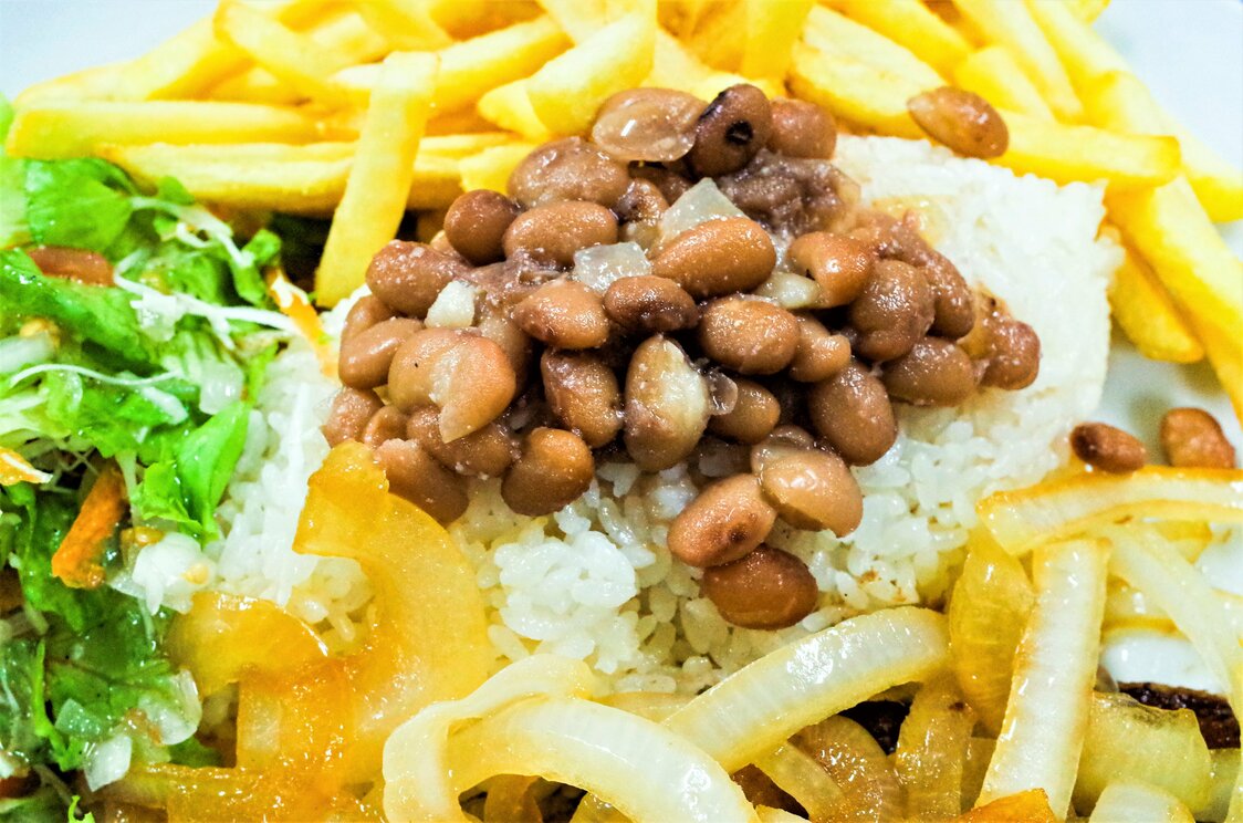 扣在白飯上的是「feijão(豆子)」。巴西最有代表性的家庭料理，拌在一起吃是當地的道地吃法（淵貴之攝影）